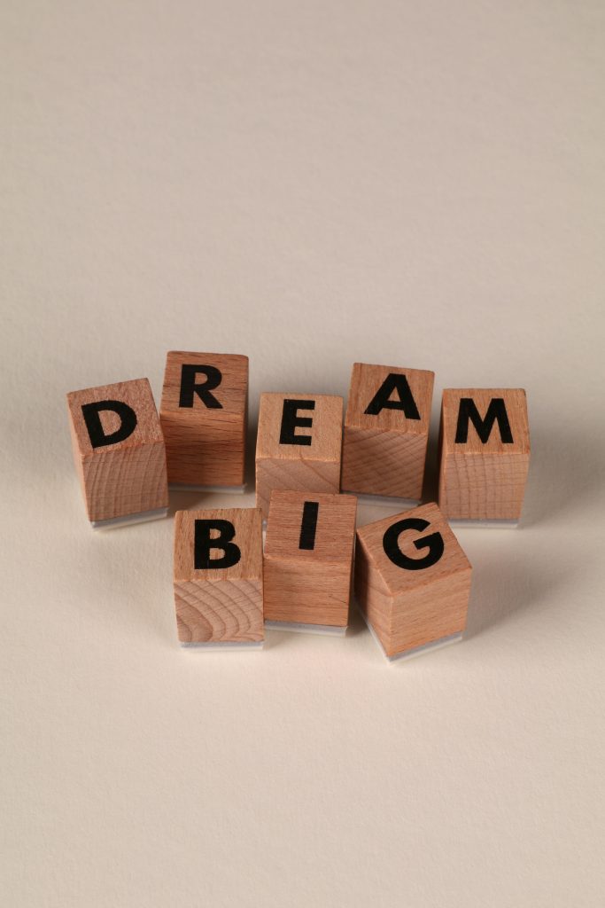 Wooden blocks with letters spelling 'Dream Big' on a neutral background, symbolizing motivation.